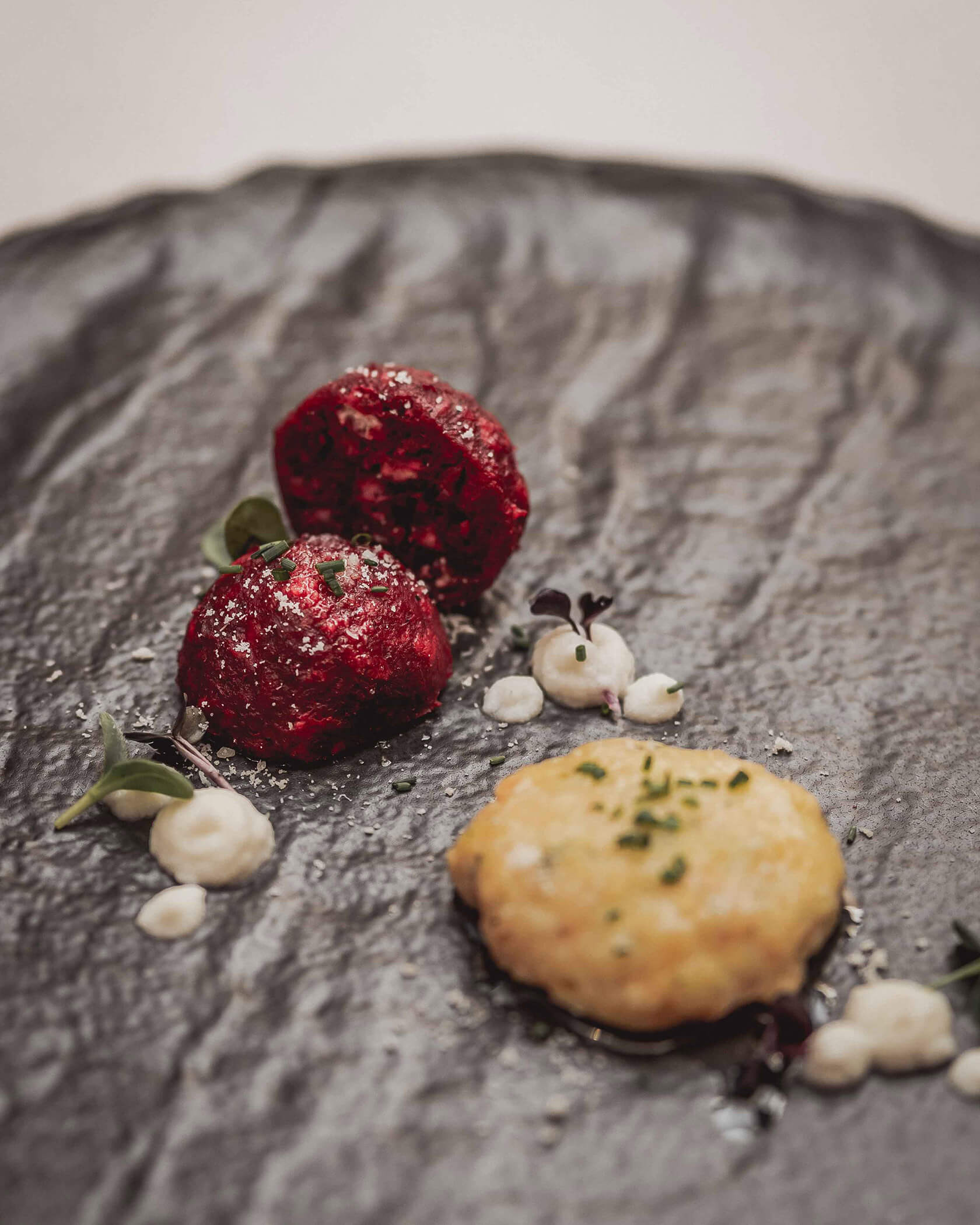 Rohnenknödel auf schwarzen Teller mit Dekoration - Hotel Continental