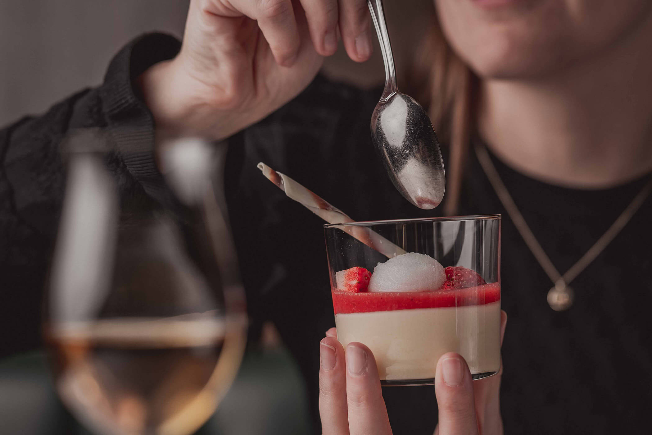 Woman enjoys white chocolate mousse with strawberry sauce and fresh strawberries - Hotel Continental