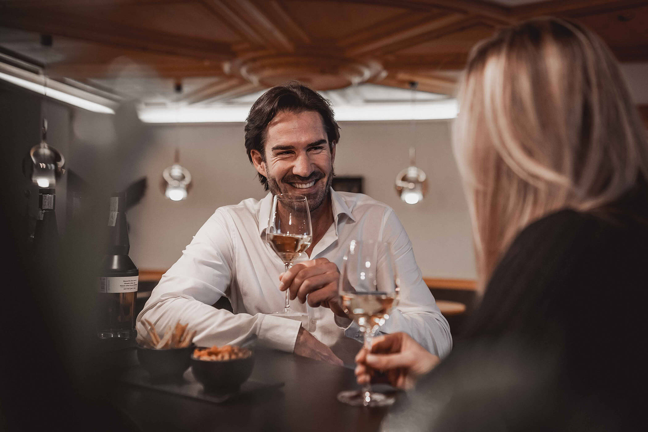A woman and a man in conversation over a glass of wine at the bar - Hotel Continental