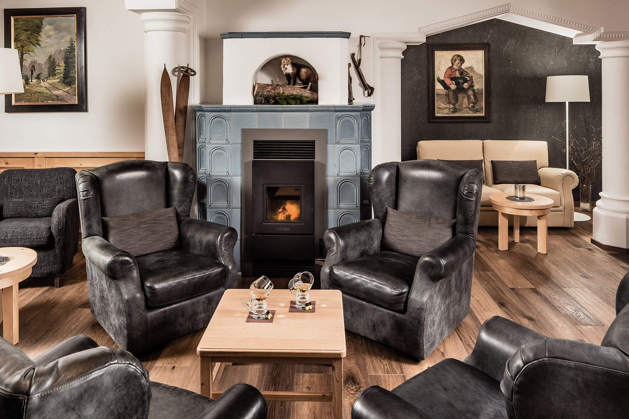 Four dark armchairs with a wooden table in the middle and a fireplace in the background - Hotel Continental