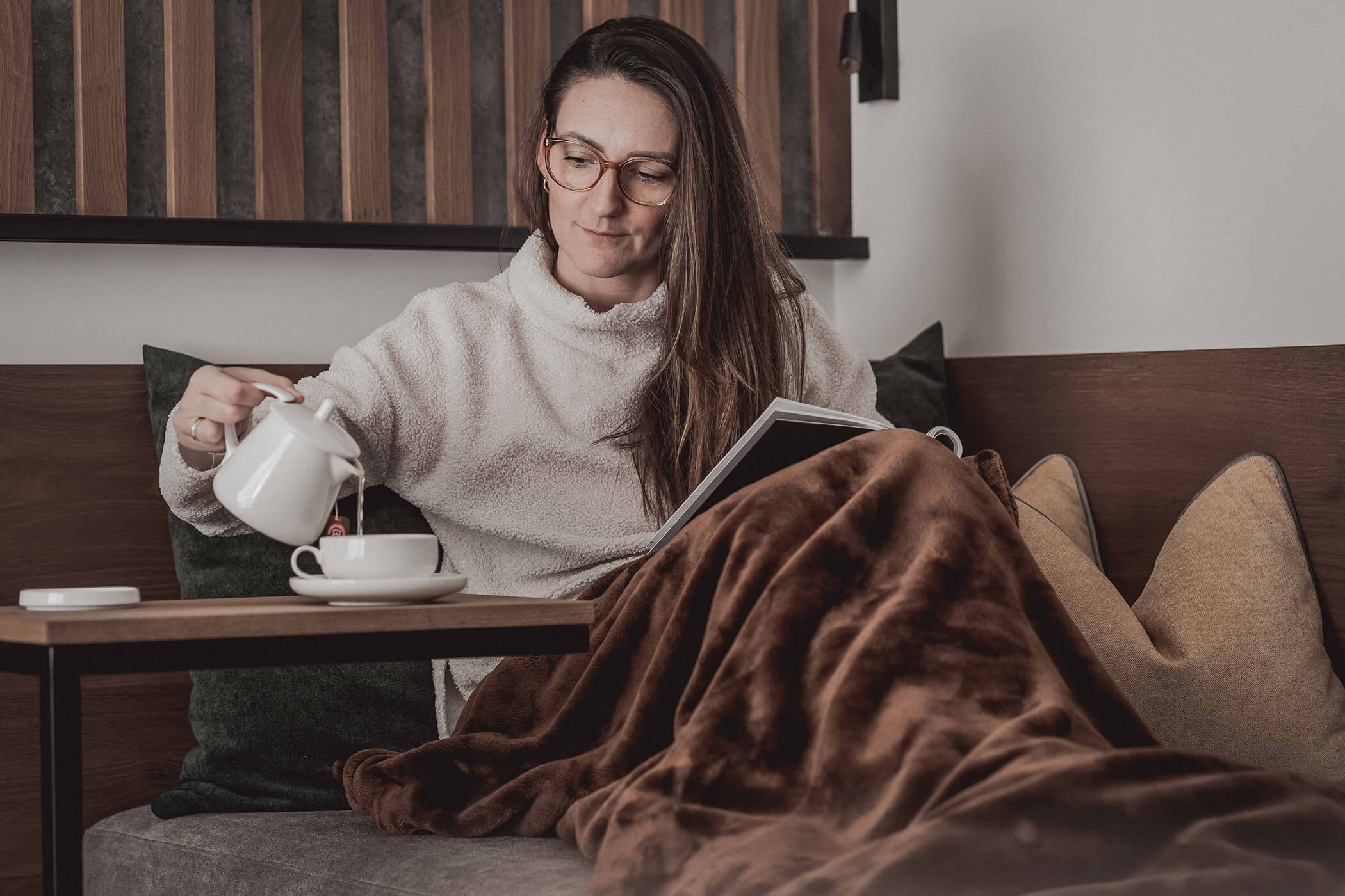 Woman reading a book and pouring tea into a cup - Hotel Continental