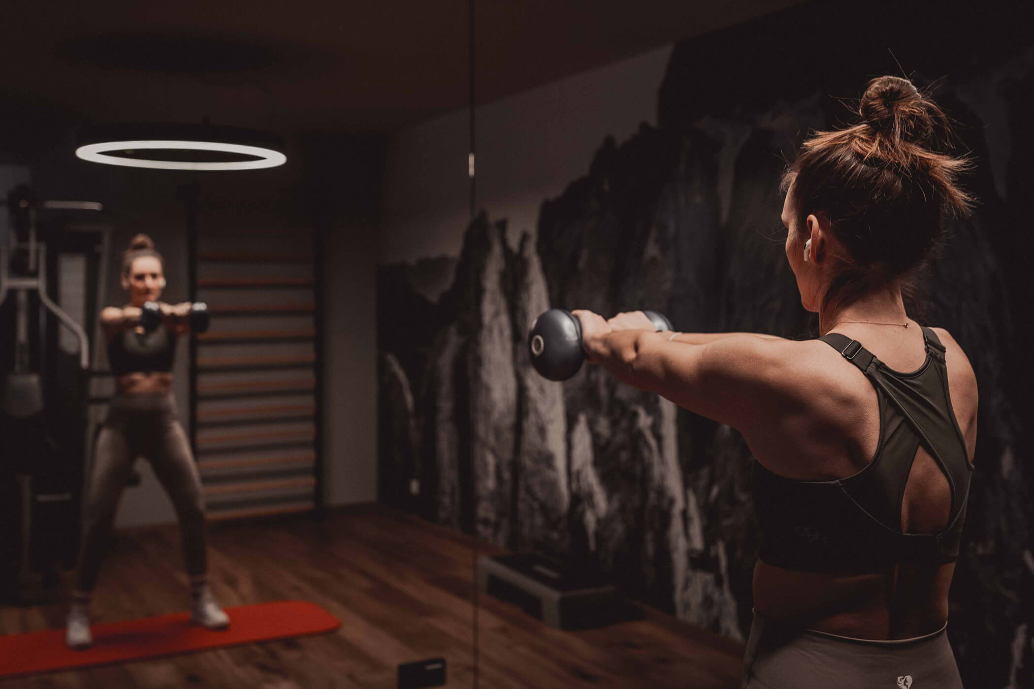 Woman holding dumbbell and looking in the mirror - Hotel Continental