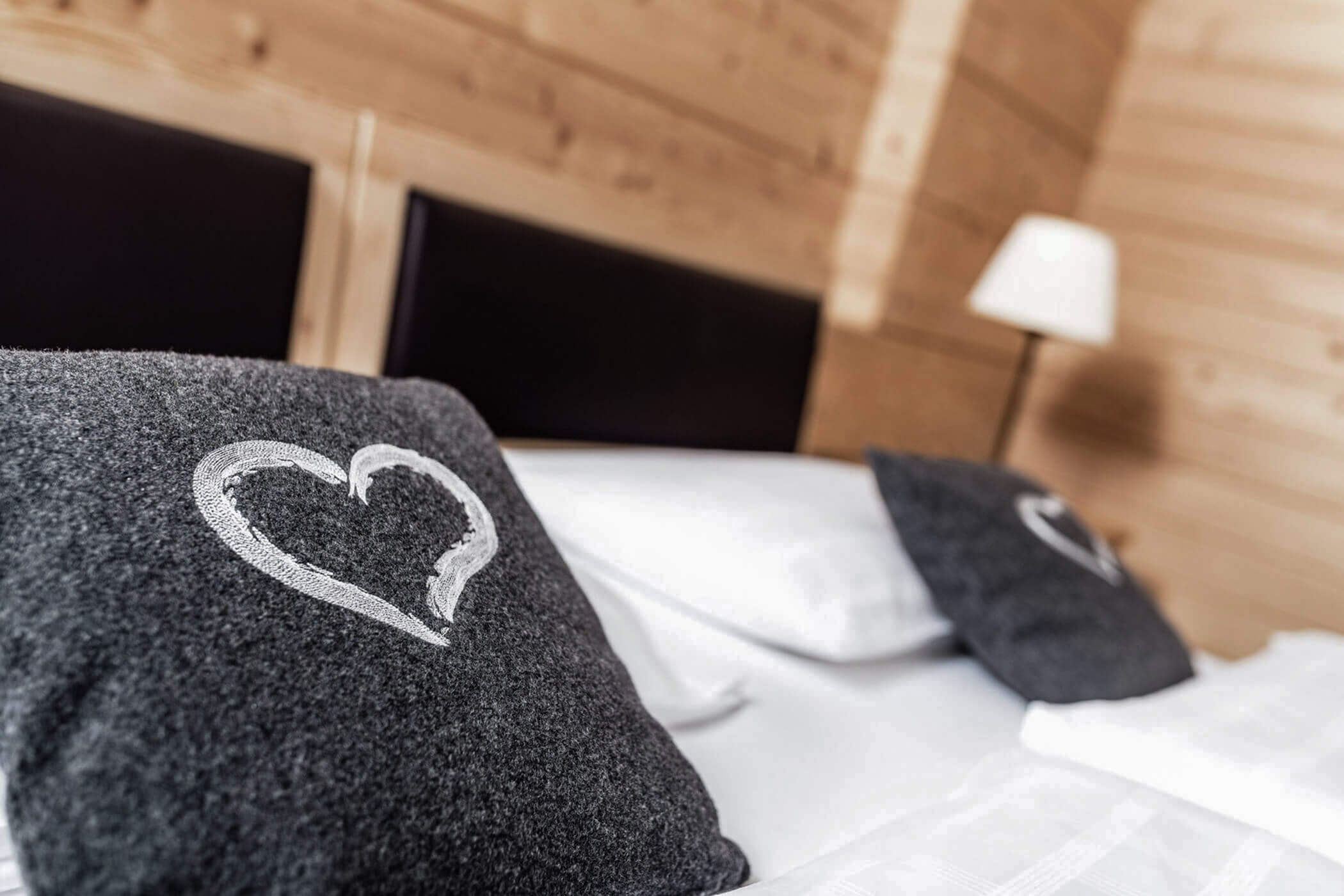 Two dark gray pillows with a heart on them in the double bed in the Classic Junior Suite 