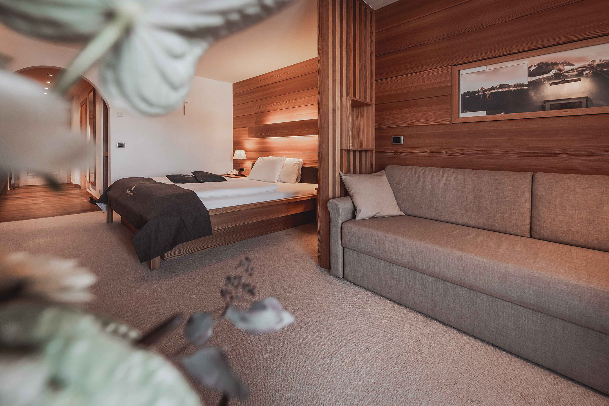Gray sofa with carpet and double bed in the background in the Classic Junior Suite 