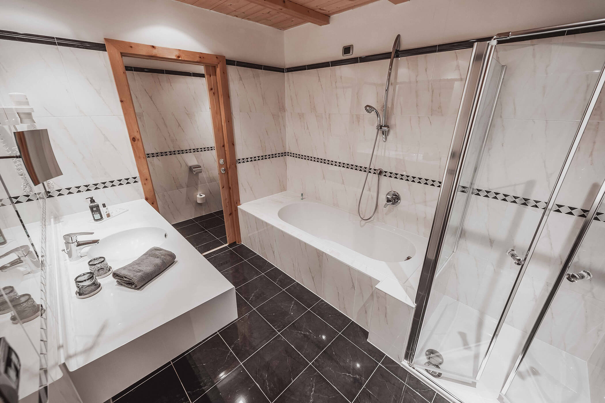 Bright bathroom with dark floor, bathtub, shower and washbasin in the Classic Junior Suite 