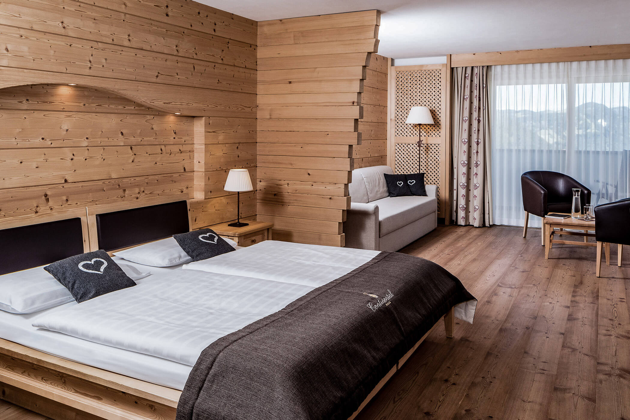 Double bed in the foreground and bright sofa in the background in the Classic Junior Suite 