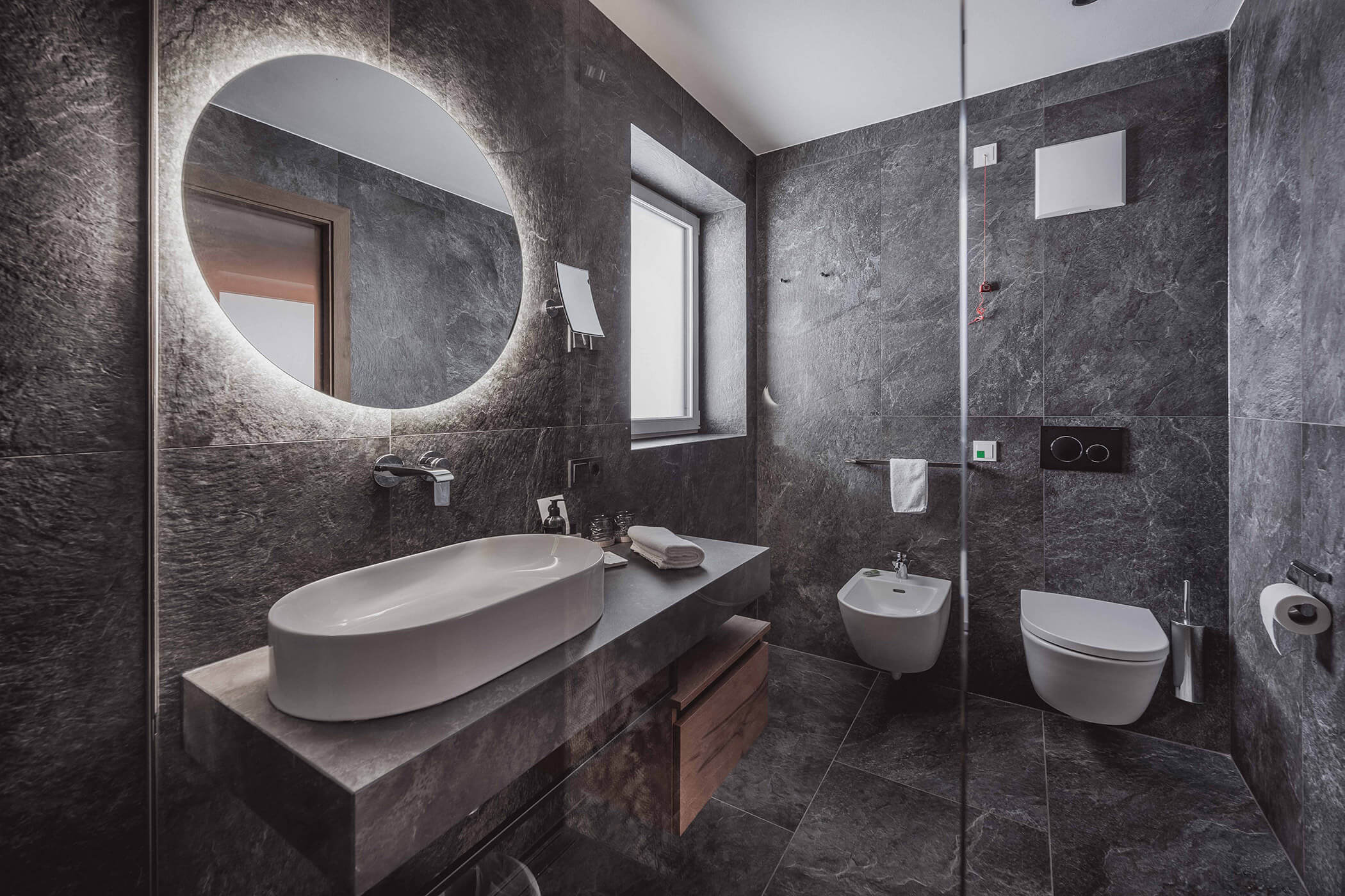Dark stone bathroom with sink, mirror and toilet - Hotel Continental