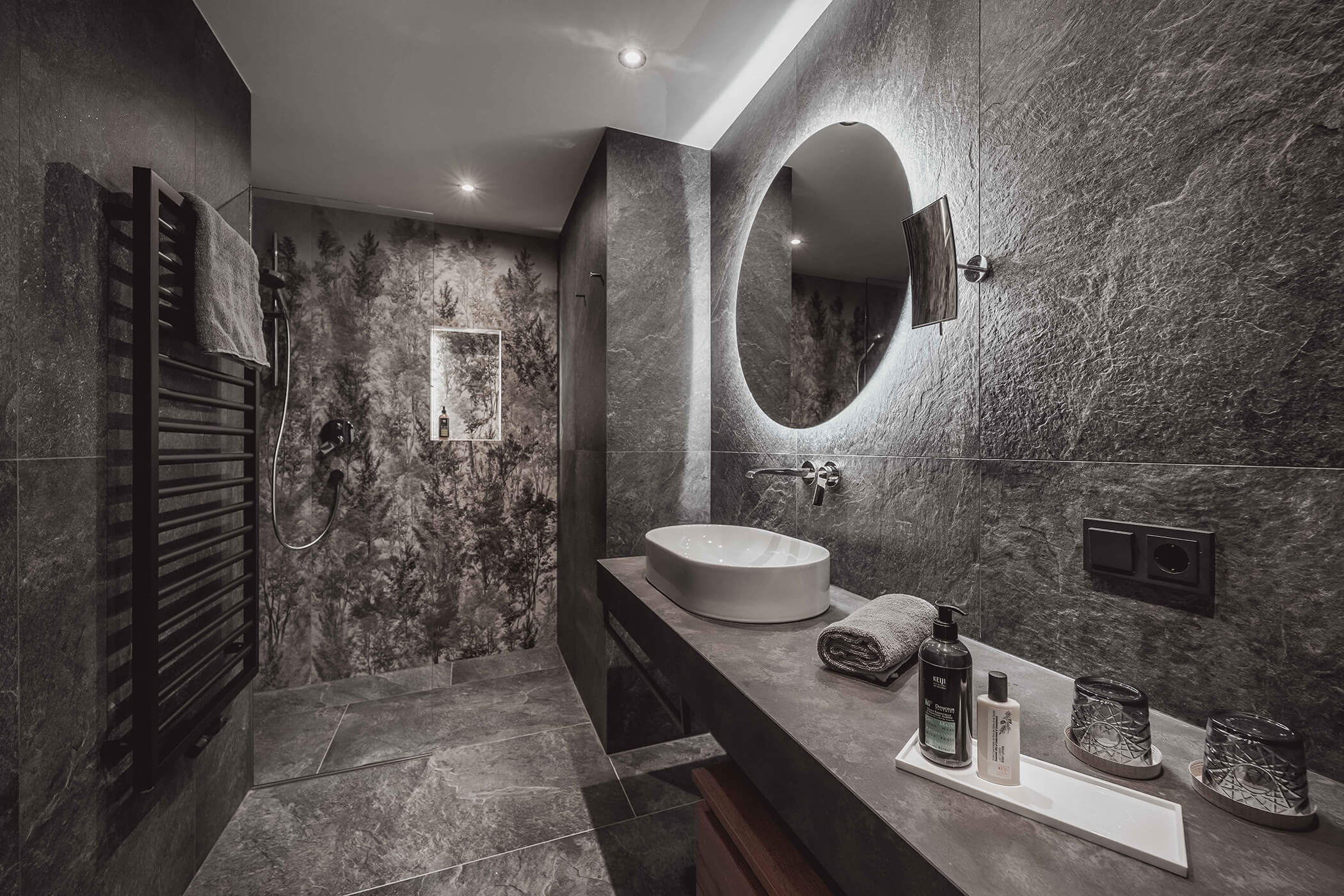 Modern, dark bathroom with washbasin and round mirror in the 