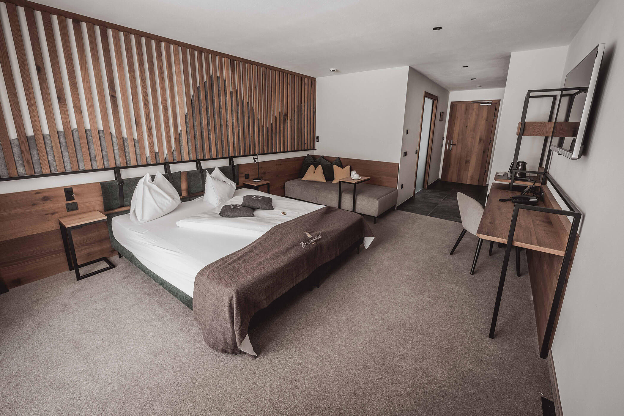 Superior double room with a view of the double bed and a dashed wooden wall in the background - Hotel Continental