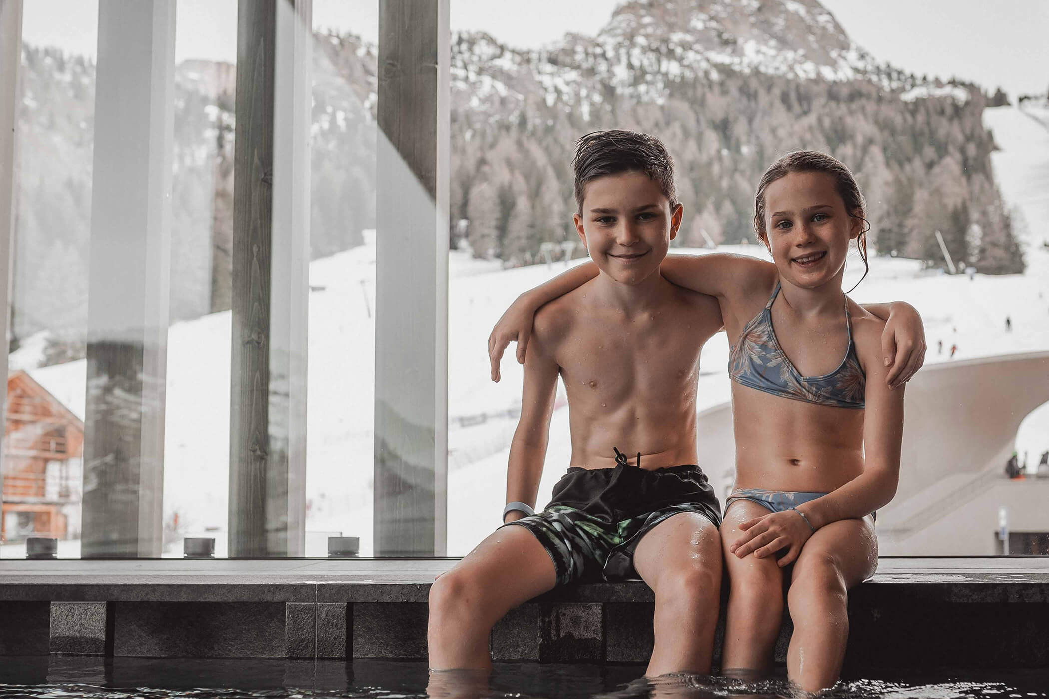 Two children sitting and laughing at the edge of the pool - Hotel Continental
